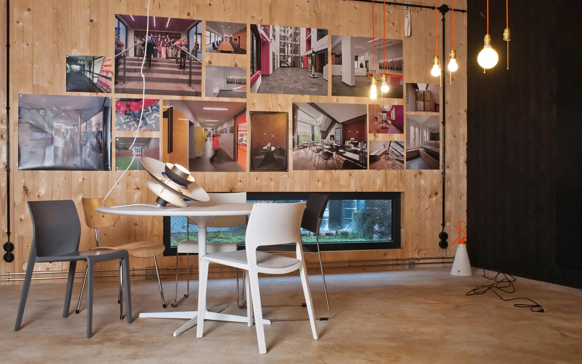 Arbeitsbereich mit großem Tisch, Materialmustern und wandhohem Regal mit Ordnern und Büchern.