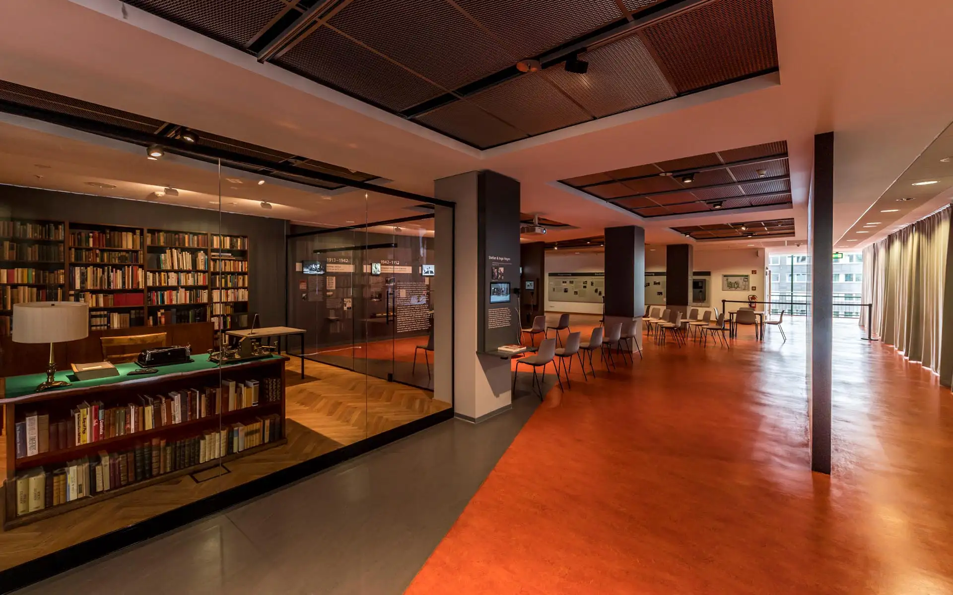 Offener Ausstellungsbereich mit Bibliotheksrekonstruktion hinter Glas links und großzügiger Sitz- und Präsentationszone mit Fensterfront rechts
