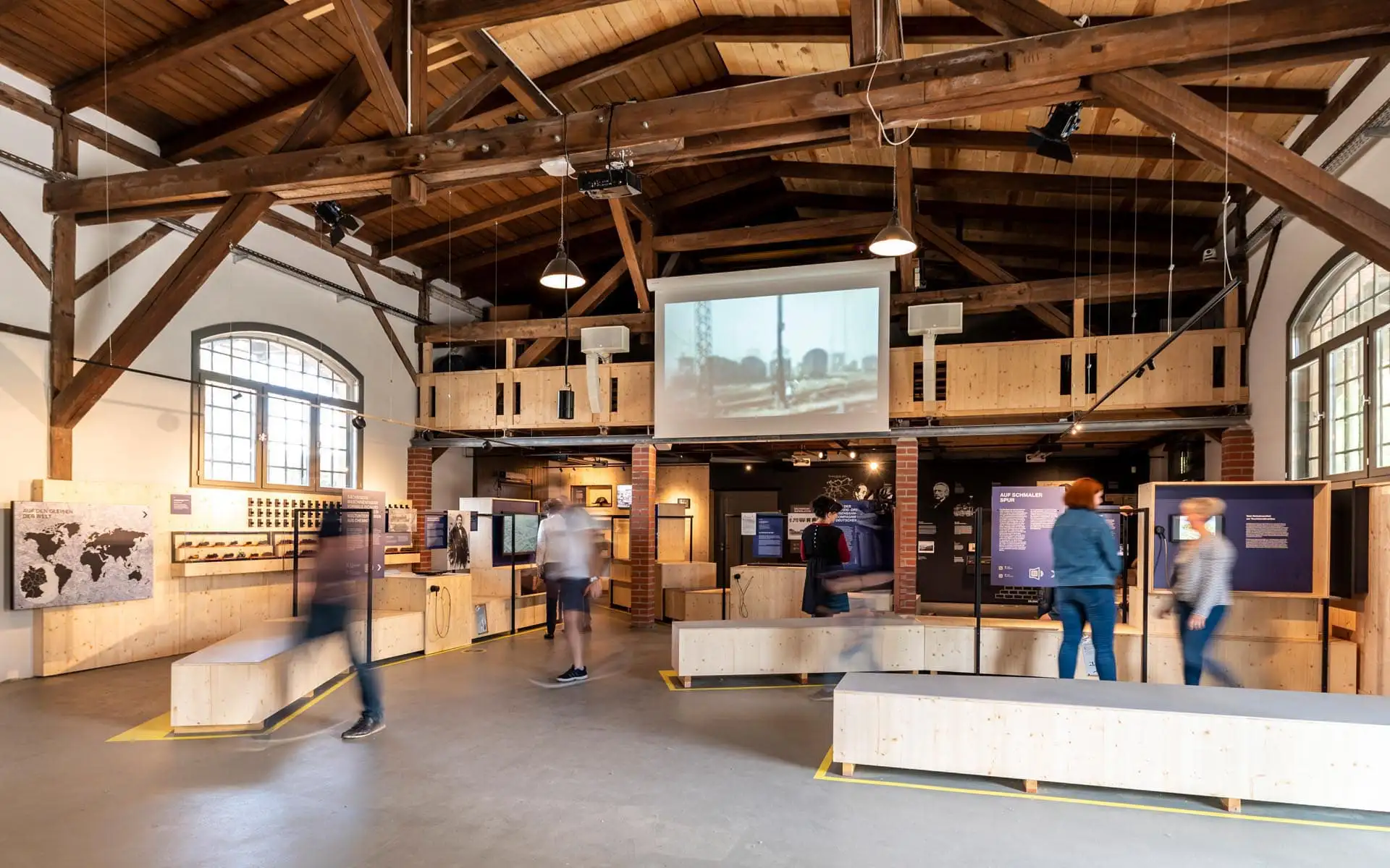 Vater mit Kind betrachtet Lokmodell in einer Wandvitrine