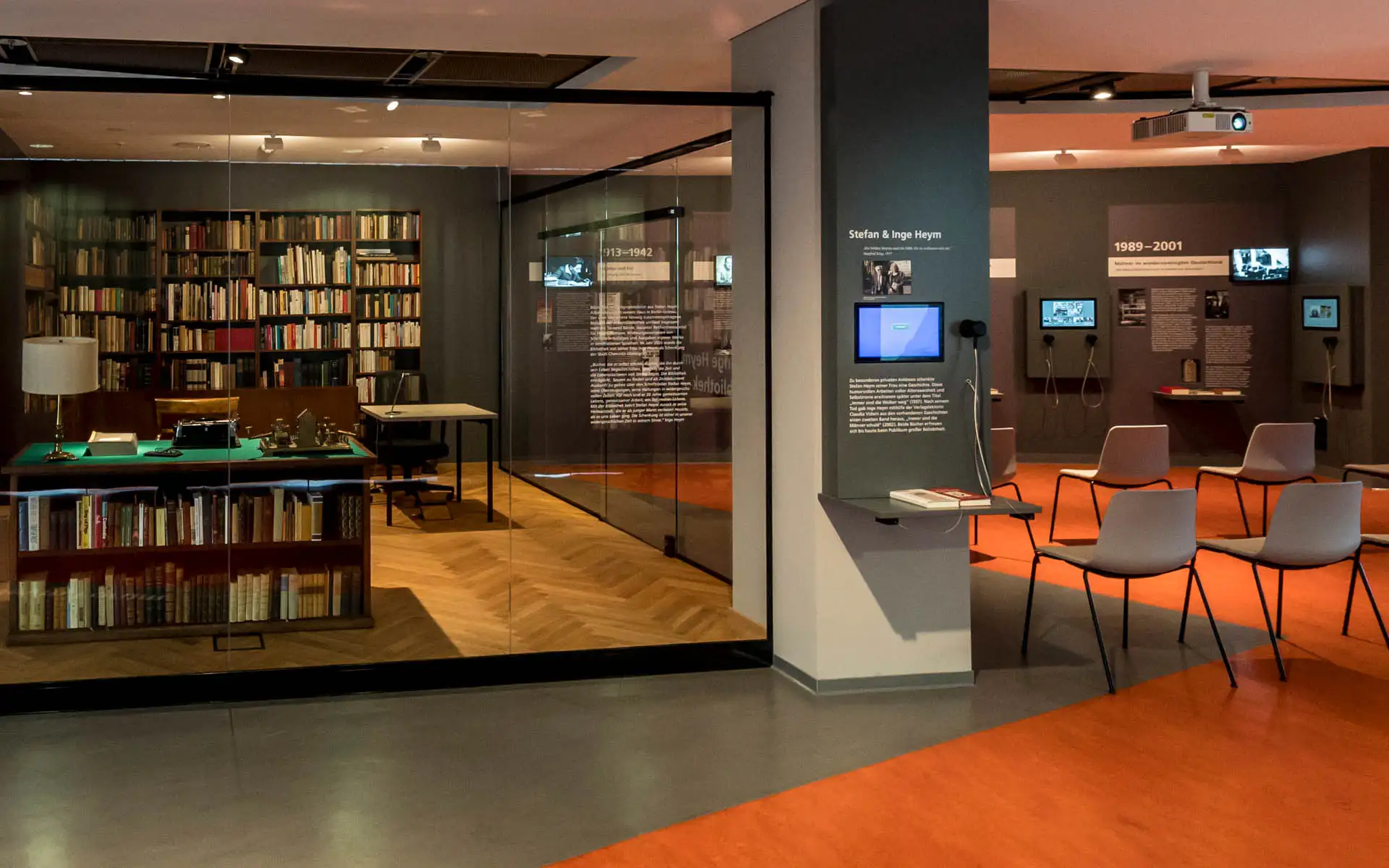 Ansicht auf Schreibtisch-Vitrine und Arbeitsbibliothek links sowie Medienstationen und Bestuhlungsbereich rechts im Stefan-Heym-Forum