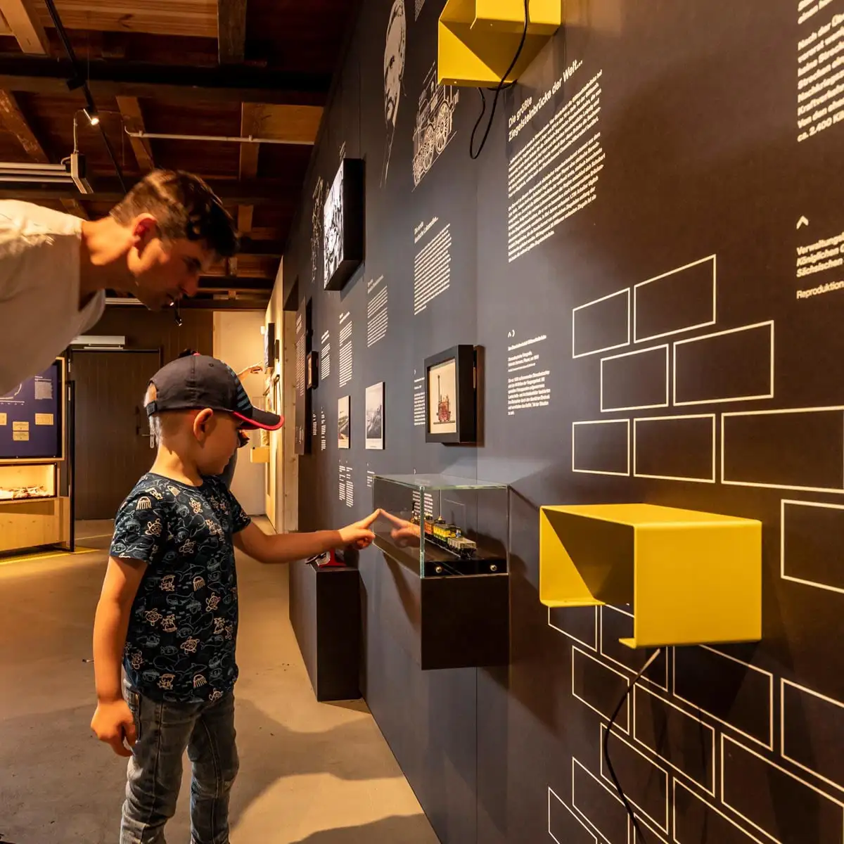 Kind bedient interaktiven Bildschirm, daneben großes Porträtfoto