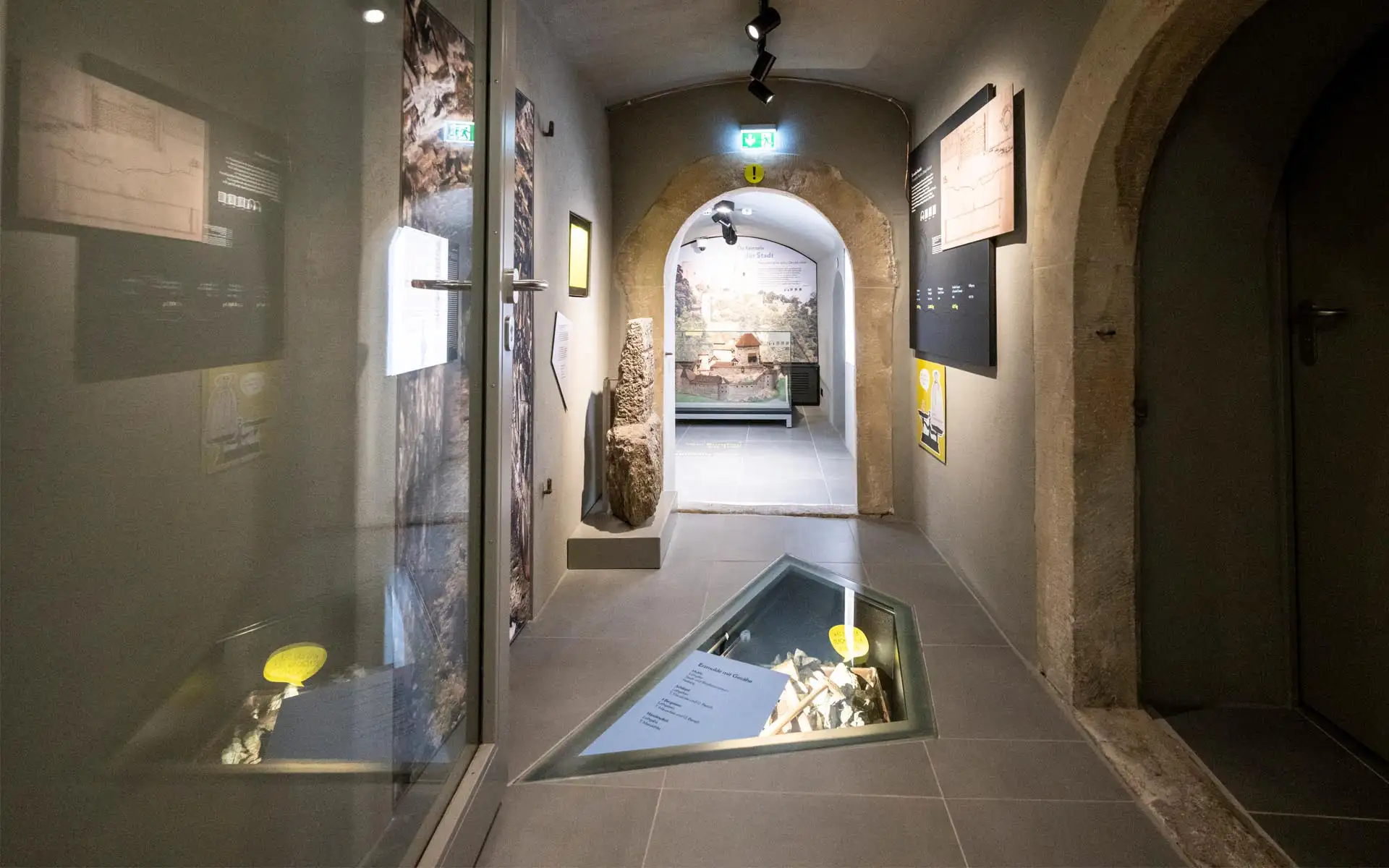 Mitmach-Station: Kinder bauen mit Holzklötzen; interaktive Bildschirmstation im Hintergrund.