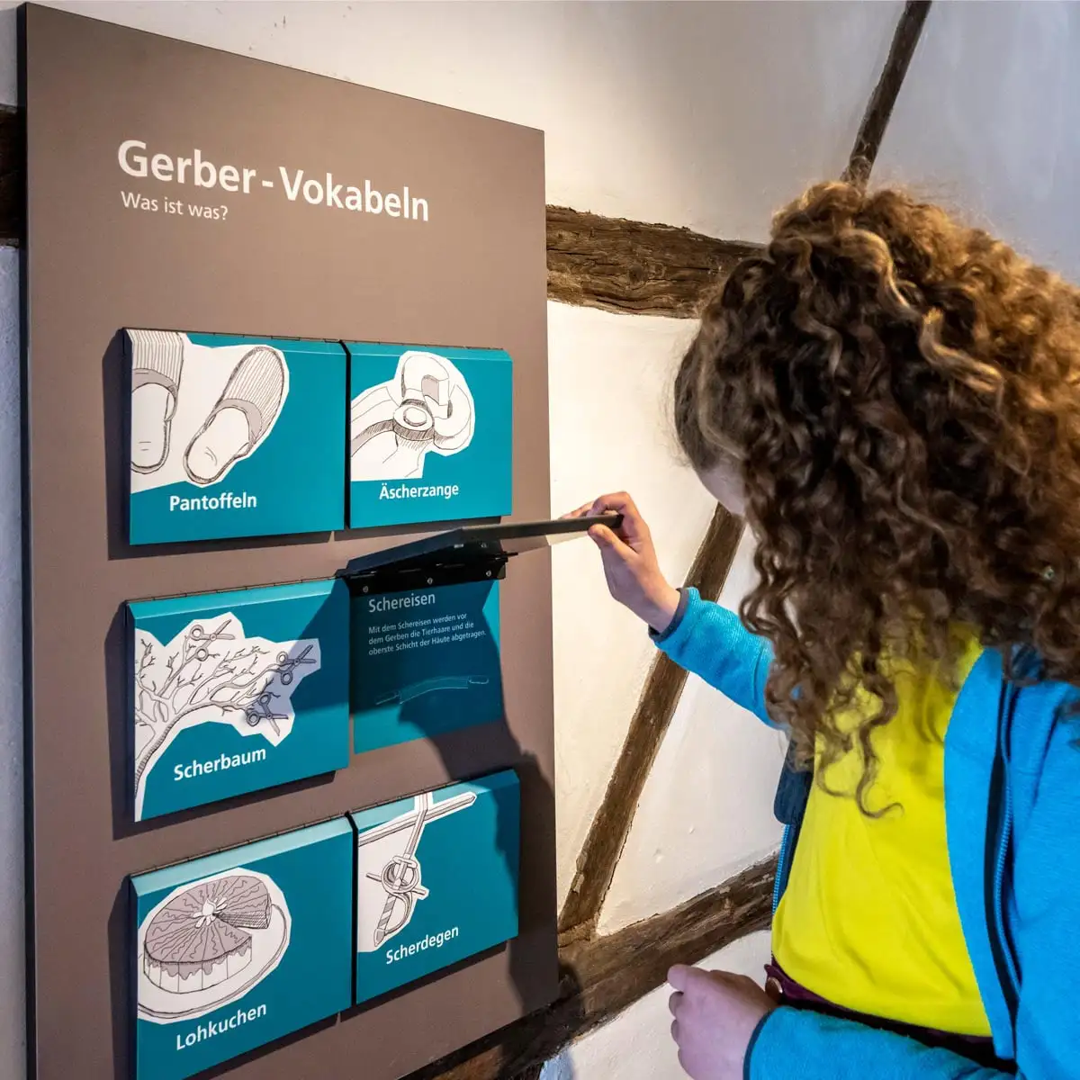 Kind hebt Klappe an der Station 'Gerber-Vokabeln'