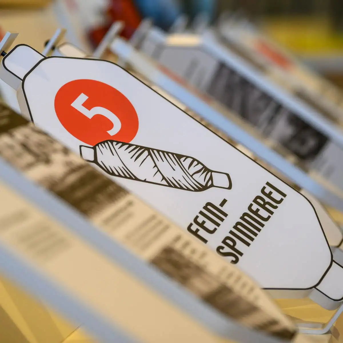 Stationsschild Fein-Spinnerei an einer Ausstellungsvitrine