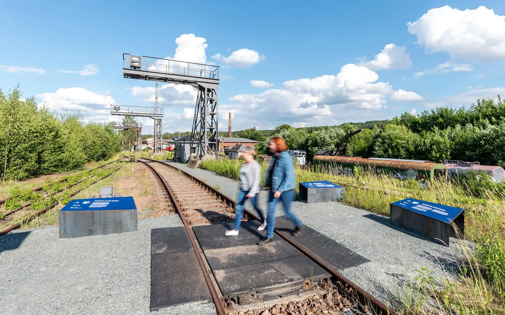 Arbeiter-Silhouetten vor weißem Güterwaggon im Freigelände