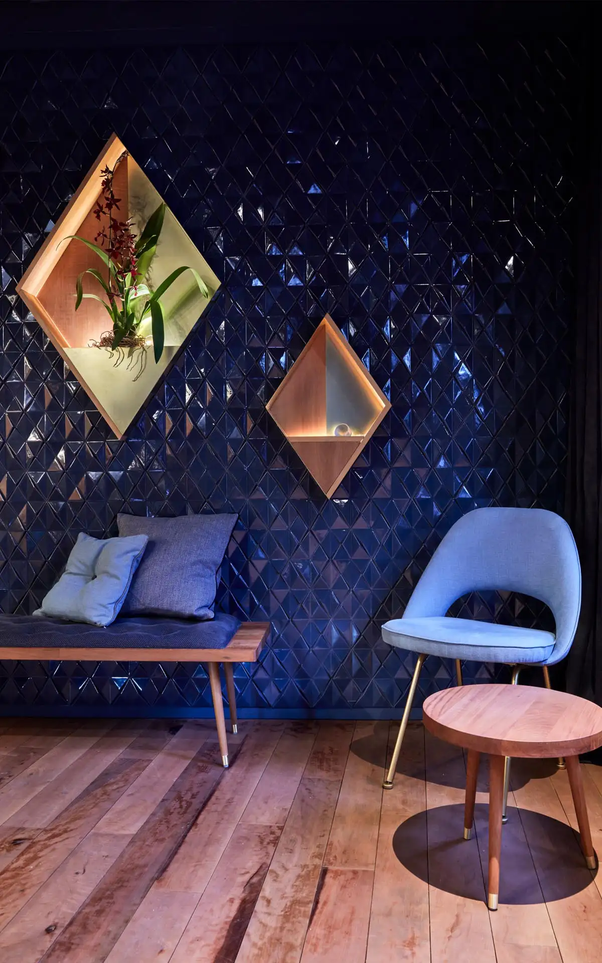 Wandnische mit Pflanze, umgeben von dunklen geometrischen Fliesen.