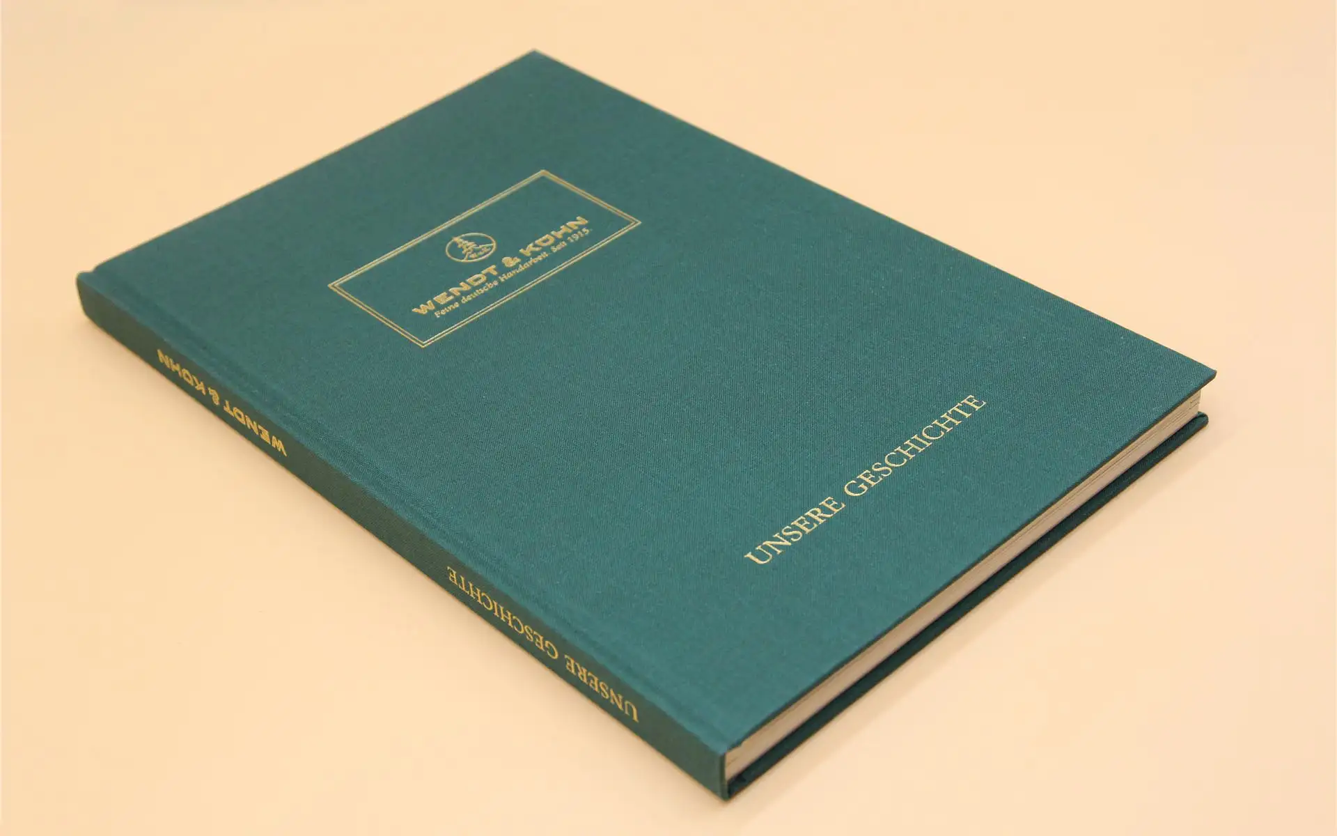 Grüner Bucheinband mit Goldprägung und Titel „Unsere Geschichte“ in klassischer Typografie.