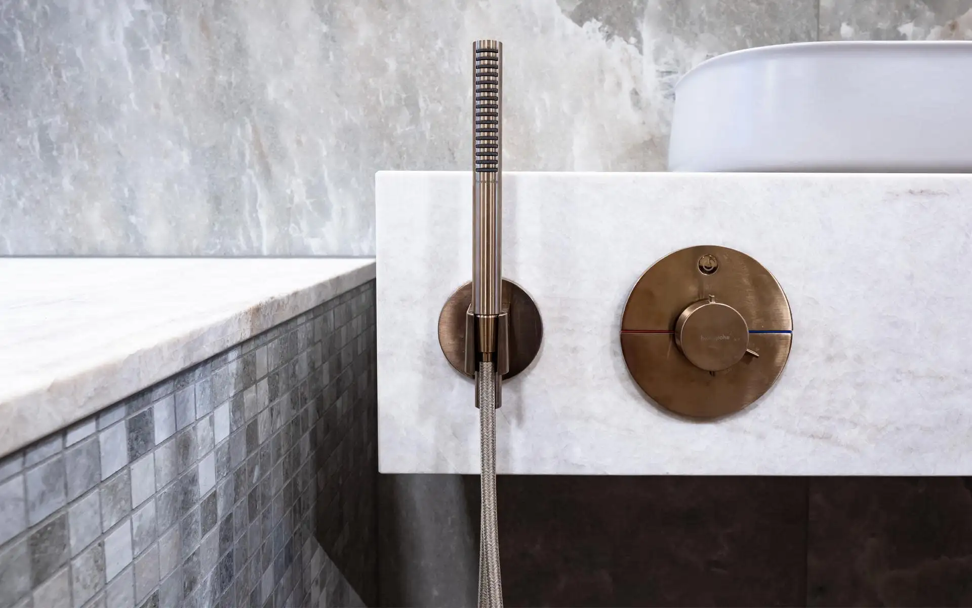 Detailaufnahme einer goldfarbenen Handbrause an weißem Marmor