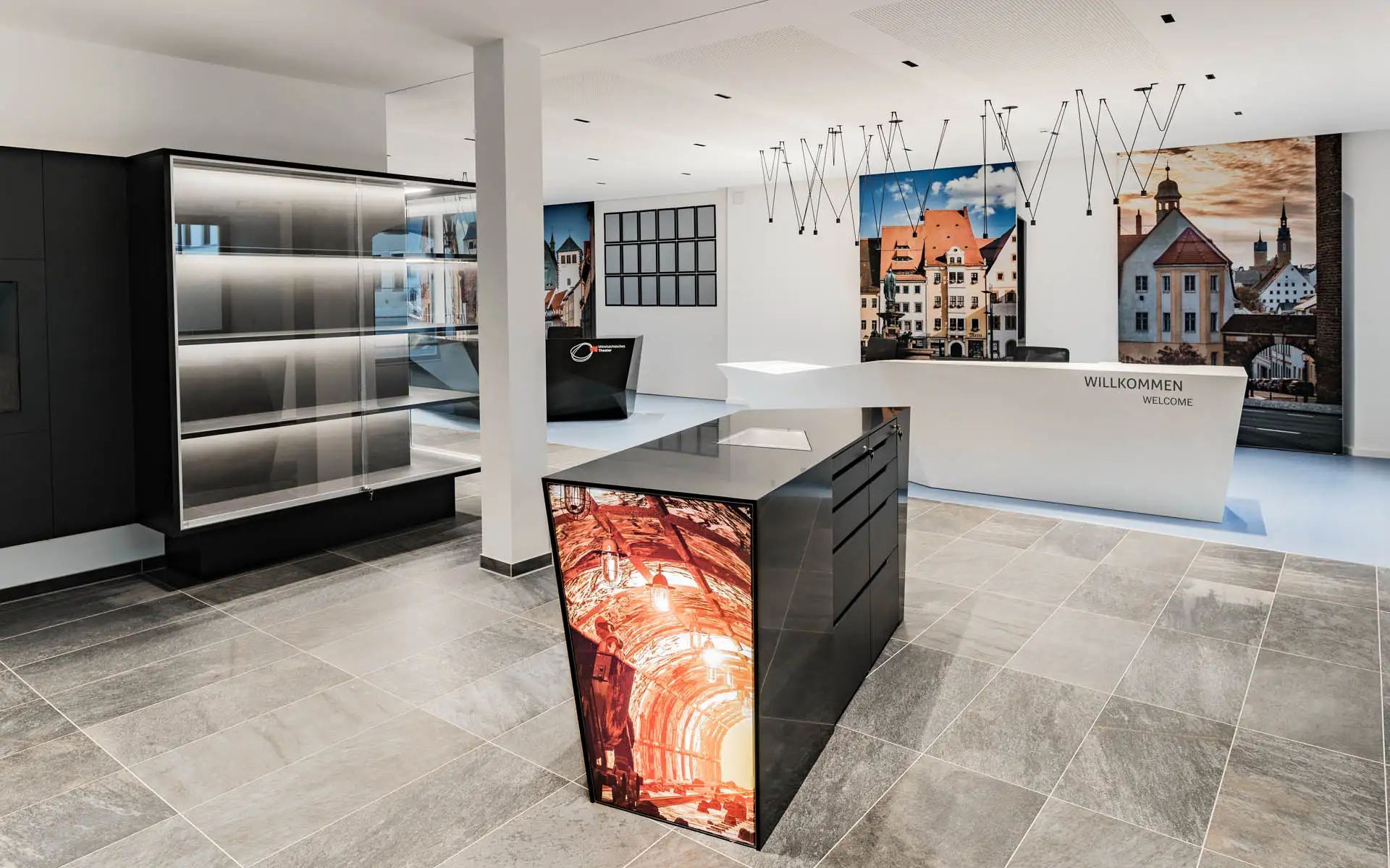 Innenraum mit Info-Tresen, vitrinenartigem Regal und beleuchteter Bildfläche am Inselmöbel