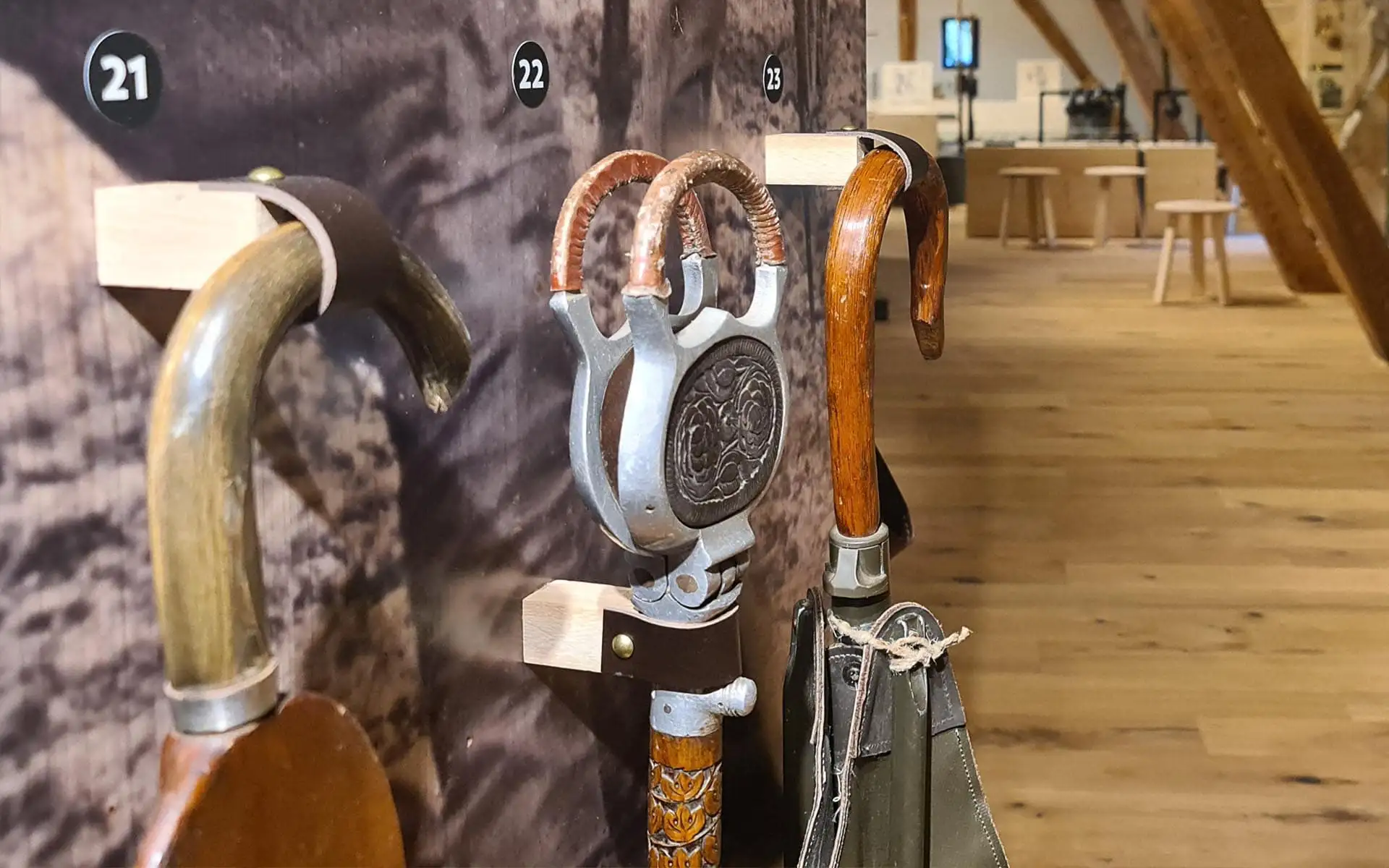 Historische Gehstöcke mit unterschiedlichen Griffen an einer Wandhalterung.