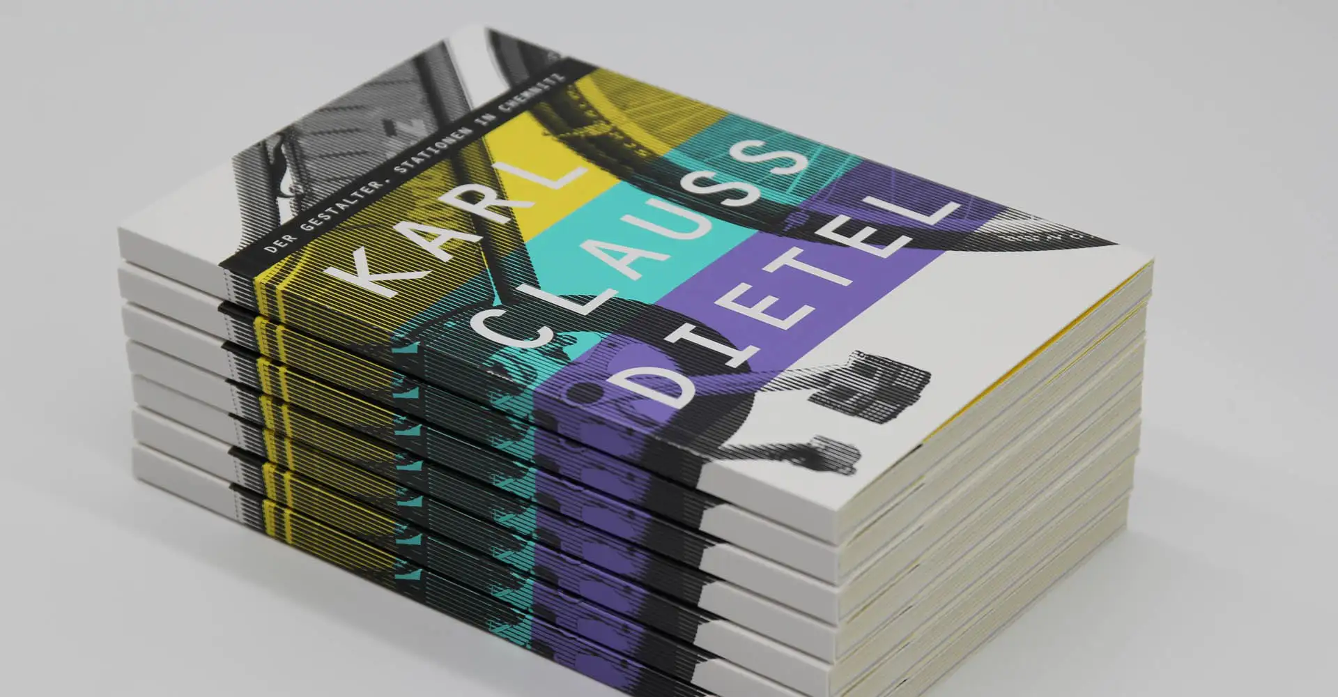 Gestapelte, farbig gestaltete Bücher mit aufgefalteter gelber Beilage.