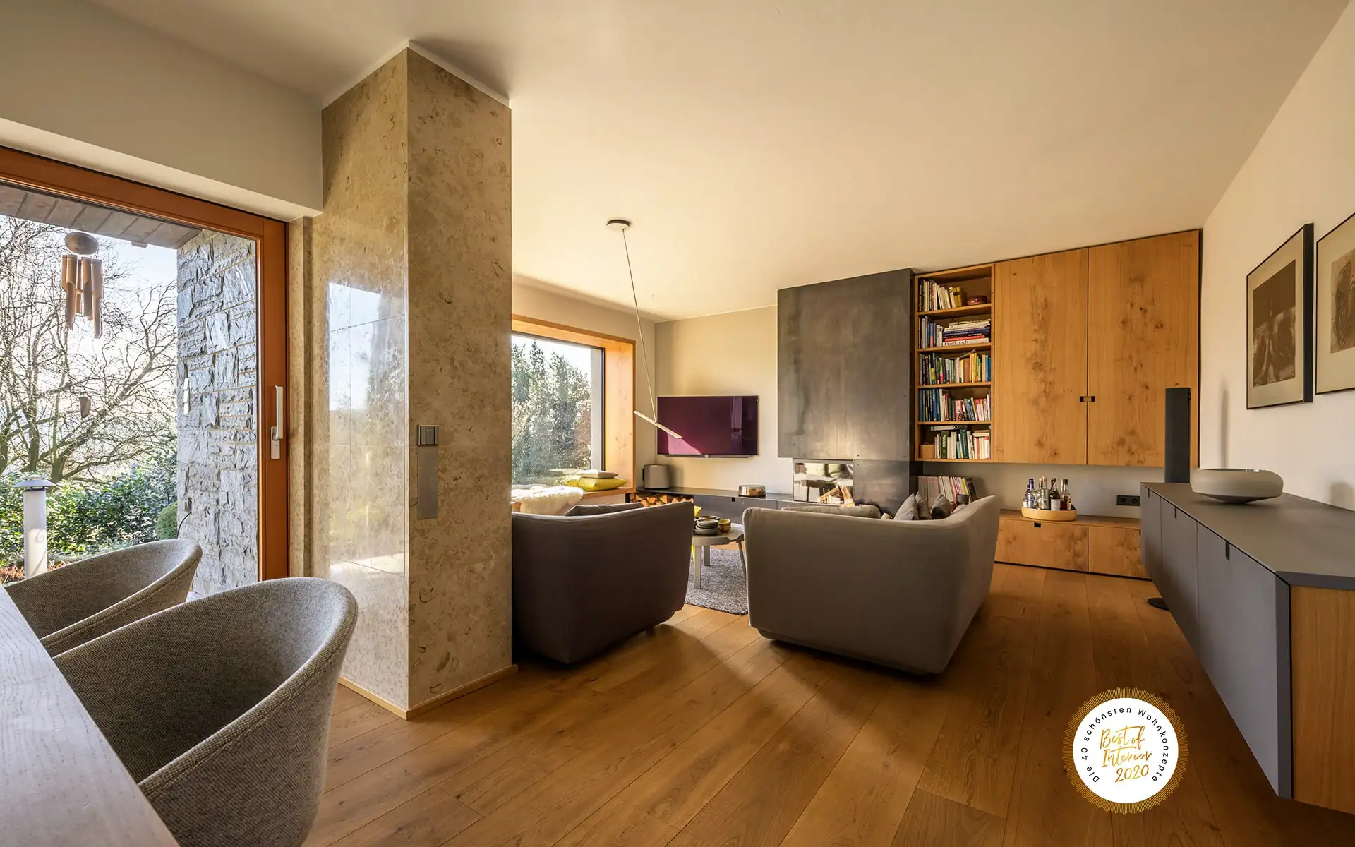 Wohnzimmer mit Panoramafenster, Kaminwand und Einbaumöbeln aus Holz.