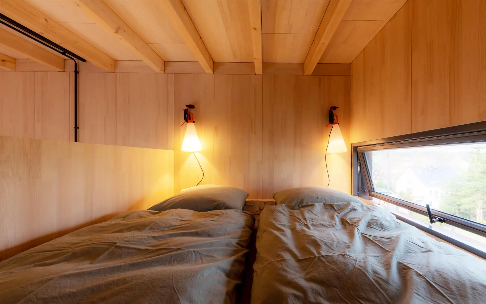 Schlafbereich mit zwei Einzelbetten, Holzverkleidung und Wandleuchten