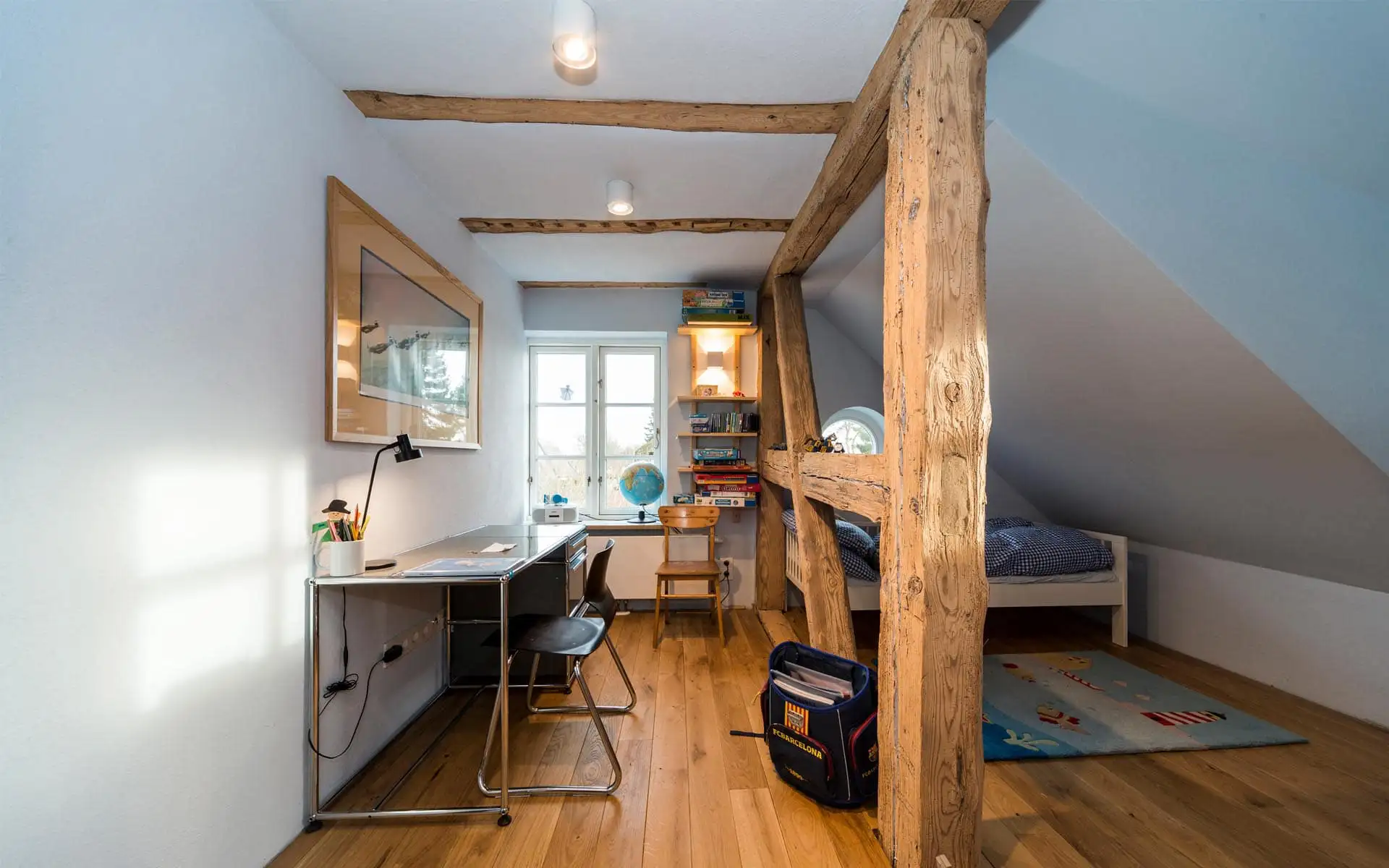 Kinderzimmer im Dachgeschoss: schmaler Arbeitsbereich, sichtbare Fachwerkstütze, Schlafnische mit Bett.